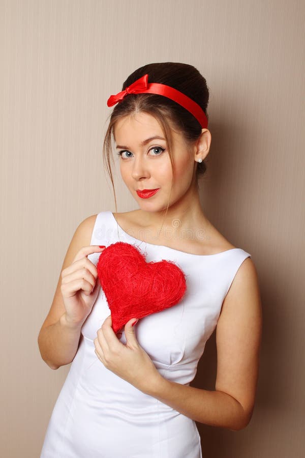 Beautiful young woman holding a red heart