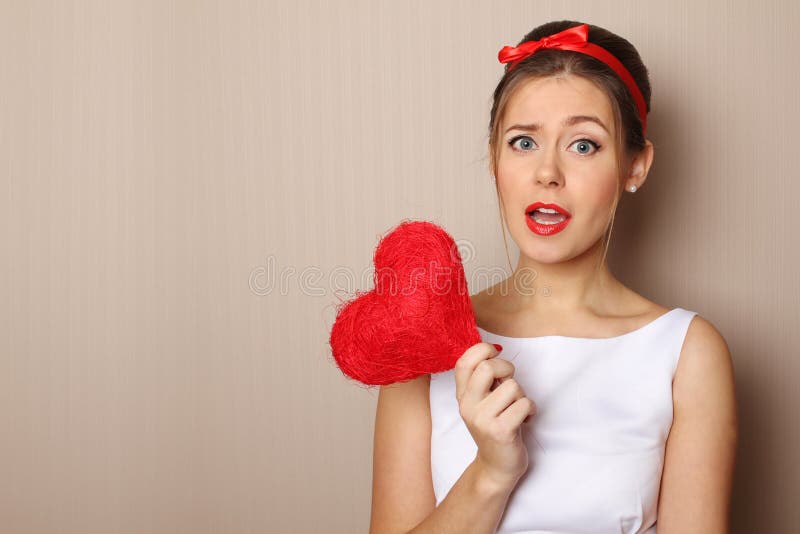 Beautiful young woman holding a red heart