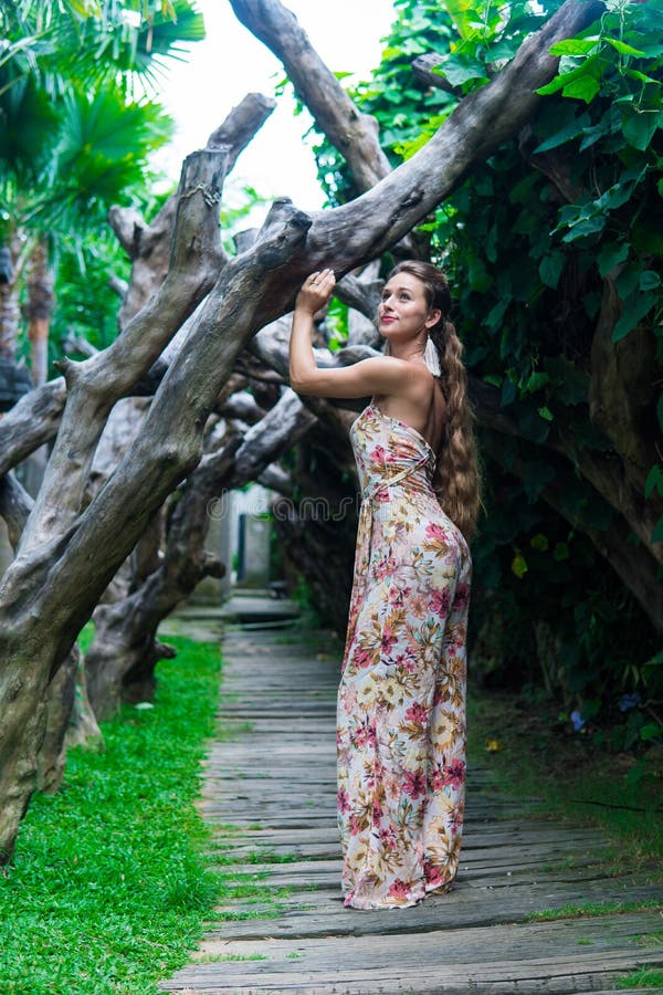 Beautiful young woman is leaning against a tree in the rain forest wearing sexy dress stock photo Beautiful young woman is leaning against a tree in the rain forest wearing sexy dress stock photo