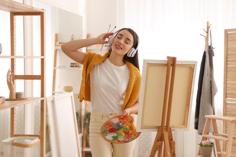 Beautiful young woman listening to music while drawing at home