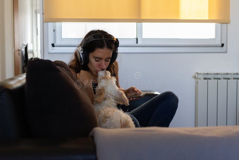 Beautiful young woman listening to music and playing with her dog