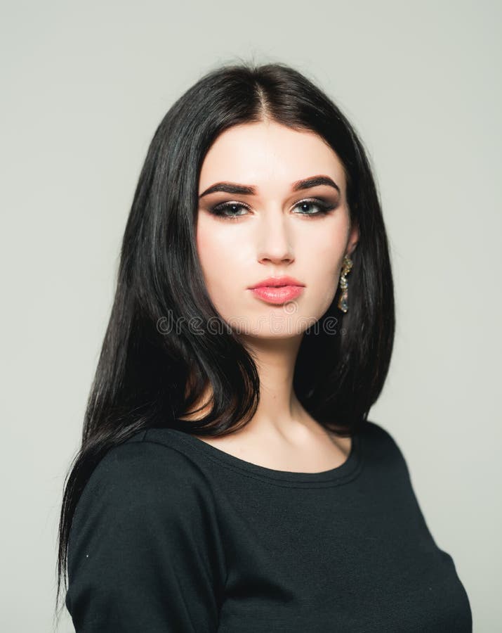 Beautiful young woman with long black hair posing in studio. Brunette smoky eyes on gray background royalty free stock images Beautiful young woman with long black hair posing in studio. Brunette smoky eyes on gray background royalty free stock images