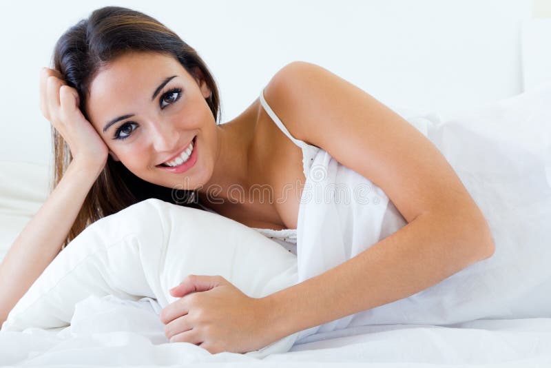 Beautiful young woman lying on bed. Isolated on white.