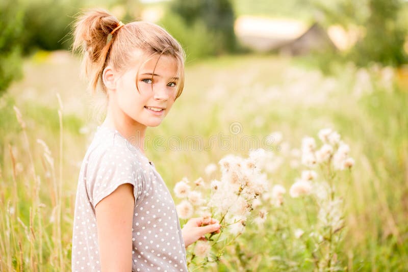 Beautiful Young Woman lying on the field in green grass and blowing dandelion. Outdoors. Enjoy Nature. Healthy Smiling Girl on spr