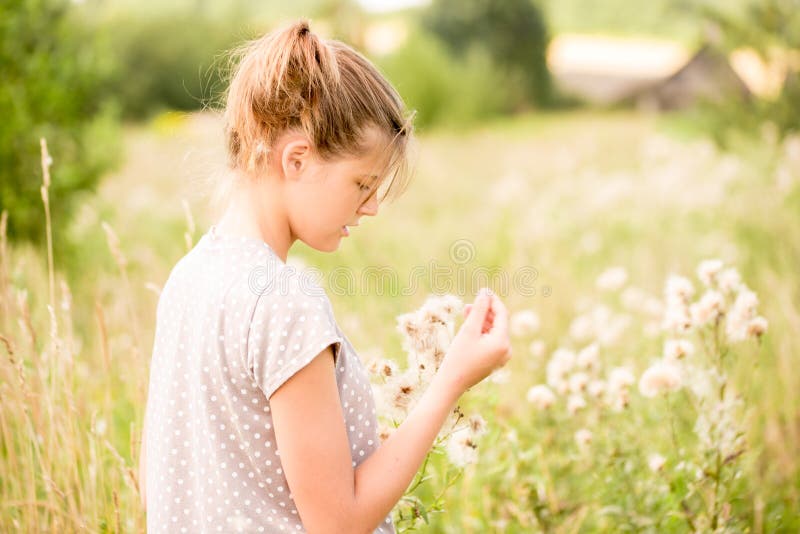 Beautiful Young Woman lying on the field in green grass and blowing dandelion. Outdoors. Enjoy Nature. Healthy Smiling Girl on spr