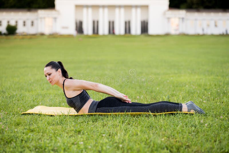 Beautiful young woman lying on a yellow mattress doing pilates or yoga, dou...