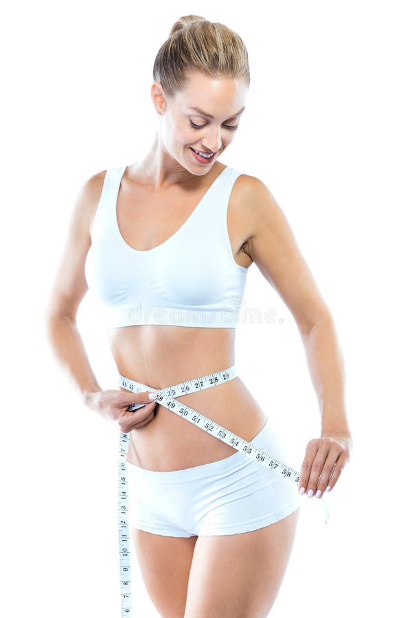 Beautiful young woman measuring her slim body over white background.