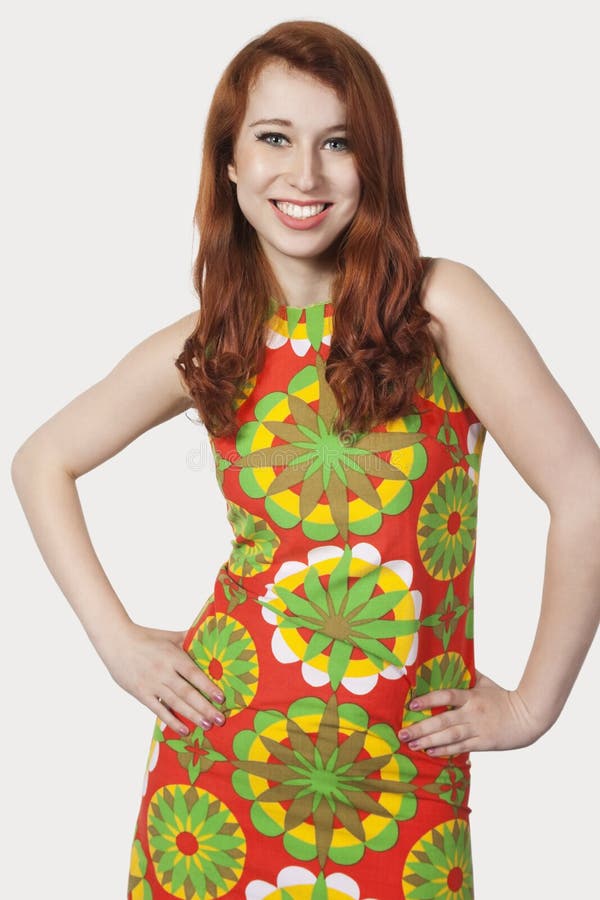 Beautiful young woman in multicolored dress posing against gray background