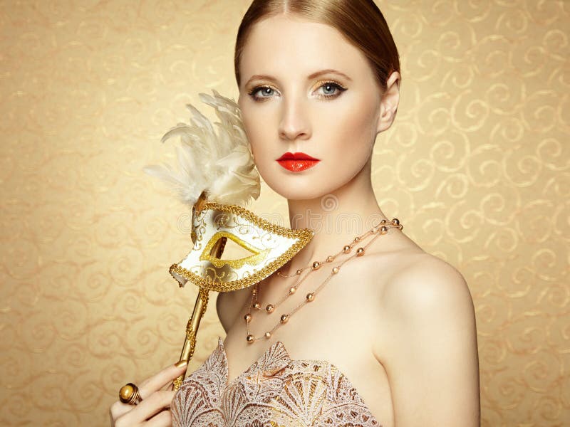 Beautiful young woman in mysterious golden Venetian mask