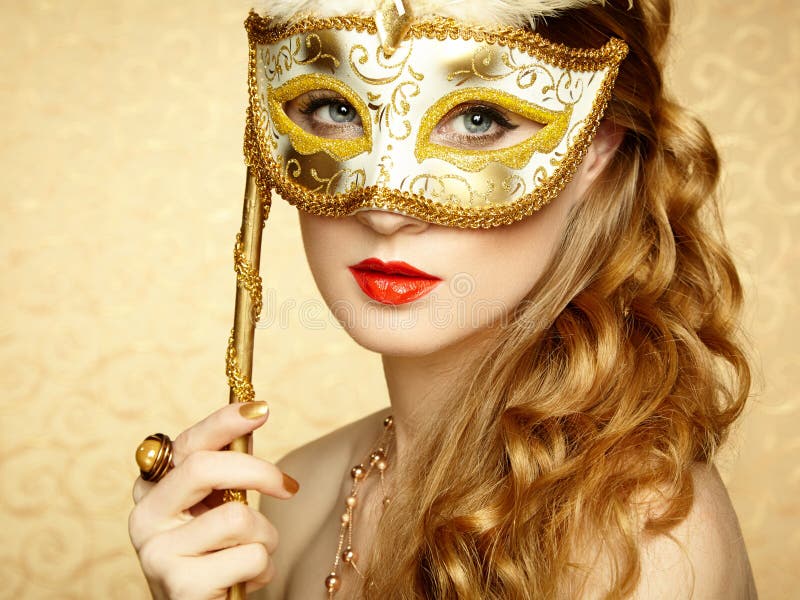 Beautiful young woman in mysterious golden Venetian mask