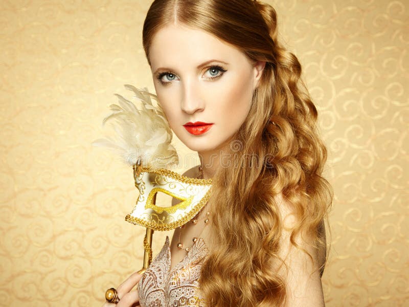 Beautiful young woman in mysterious golden Venetian mask