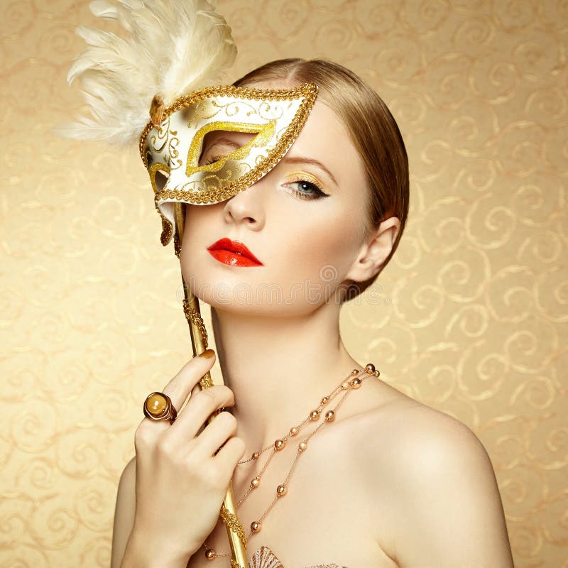 Beautiful young woman in mysterious golden Venetian mask