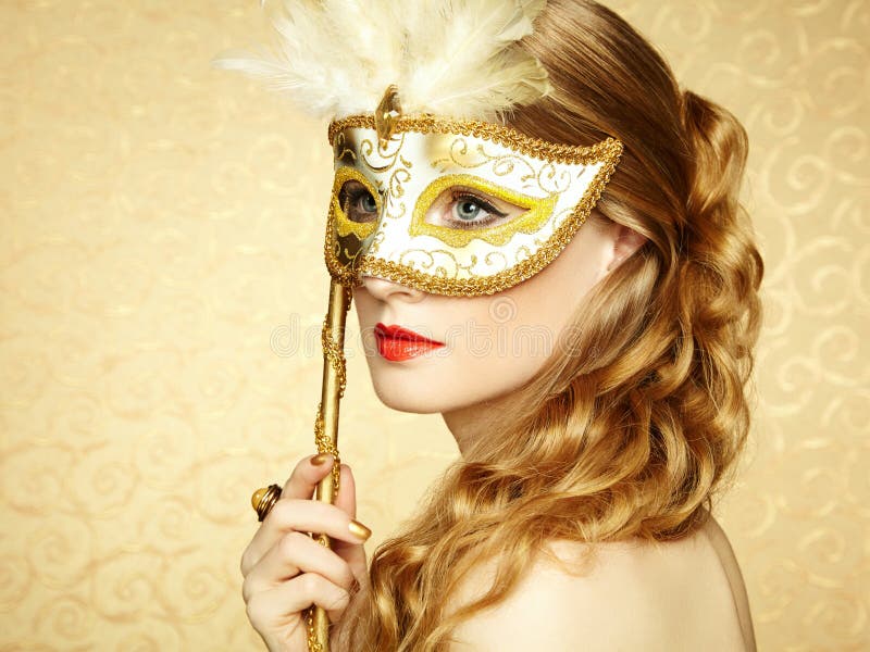 Beautiful young woman in mysterious golden Venetian mask