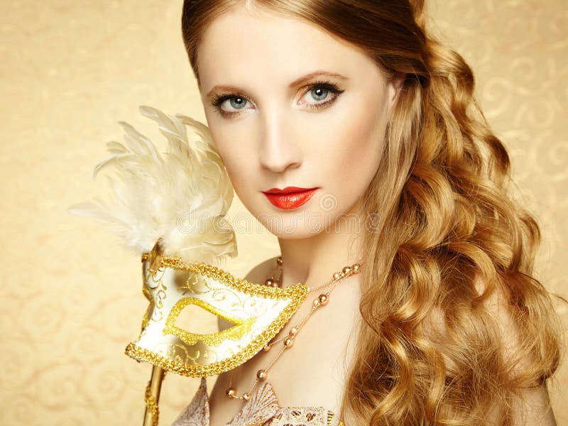 Beautiful young woman in mysterious golden Venetian mask