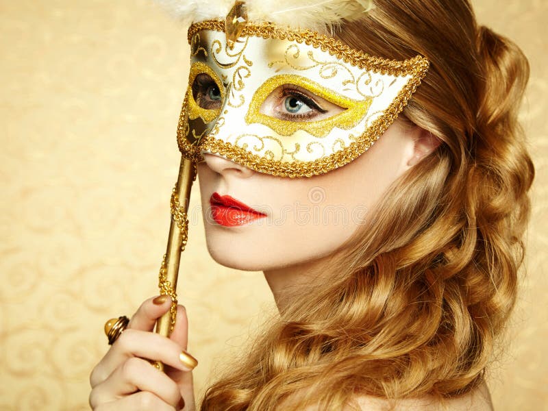 Beautiful young woman in mysterious golden Venetian mask