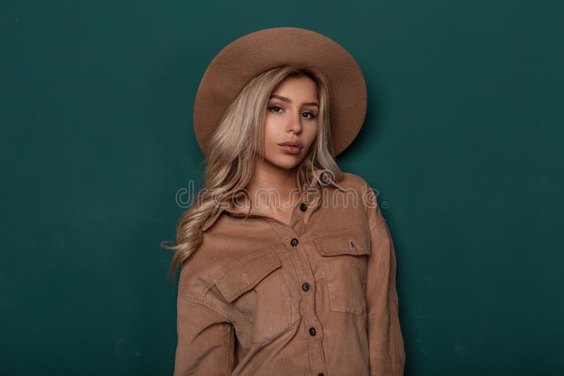 Beautiful young woman with natural make-up with brown eyes with curly blond white hair in an elegant hat