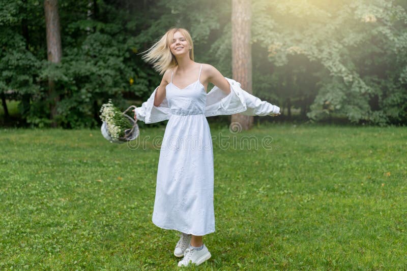 Beautiful Young Woman Outdoors holding basket with daisies. Enjoy Nature. Healthy Smiling Girl in Green Grass. royalty free stock photo Beautiful Young Woman Outdoors holding basket with daisies. Enjoy Nature. Healthy Smiling Girl in Green Grass. royalty free stock photo