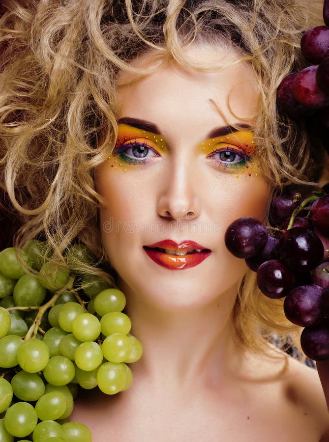 Beautiful young woman portrait excited smile with fantasy art hair makeup style, fashion girl with creative food fruit. Orange, grapes, citrus make up, happy stock photo