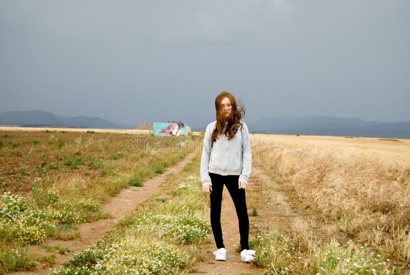 Beautiful young woman posing in a path between two wheat fields. cloudy day. Red-haired. Teenager royalty free stock photo Beautiful young woman posing in a path between two wheat fields. cloudy day. Red-haired. Teenager royalty free stock photo