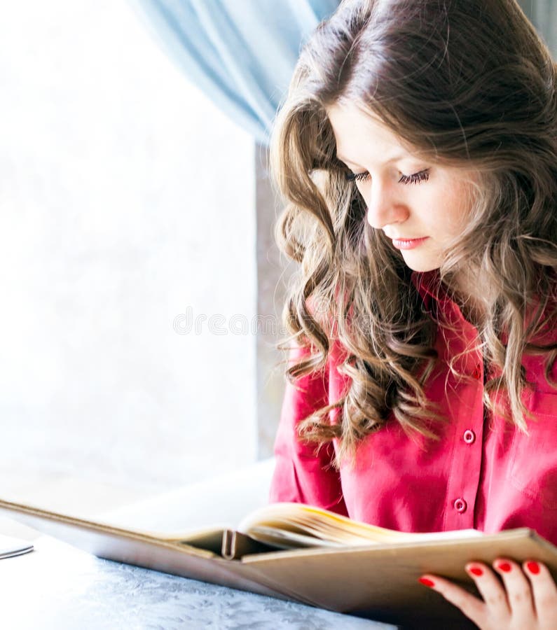 Beautiful young woman reading menu while sitting at the restaurant or cafe stock images