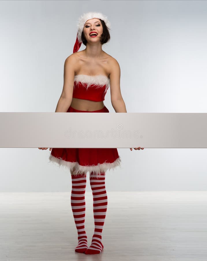 Beautiful young woman in a red skirt and Santa Claus hat holds a