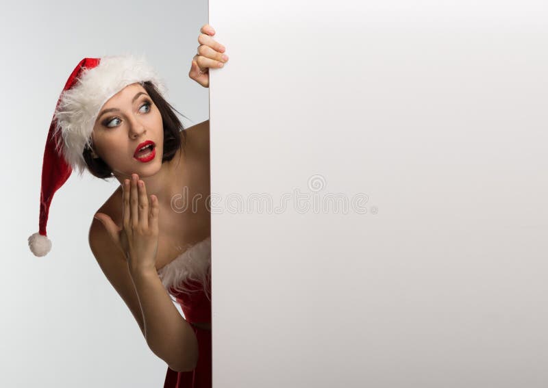 Beautiful young woman in a red skirt and Santa Claus hat holds a