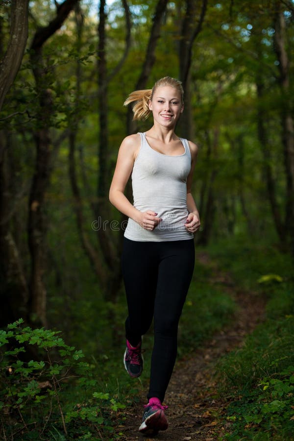 Beautiful young woman runs in forest - active runner running