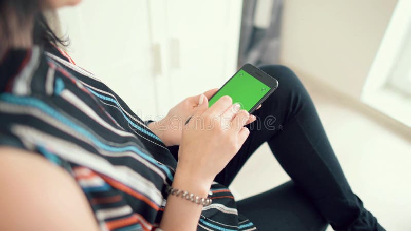 Beautiful young woman in sexy long gray dress. Beautiful girl holding a smartphone in the hands of a green screen, hand of man holding mobile smart phone with stock images Beautiful young woman in sexy long gray dress. Beautiful girl holding a smartphone in the hands of a green screen, hand of man holding mobile smart phone with stock images