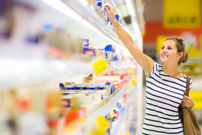 Beautiful young woman shopping for diary products at a grocery