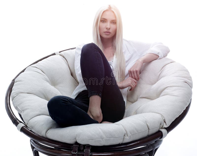 Beautiful young woman sitting on the couch in a large comfortable armchair.