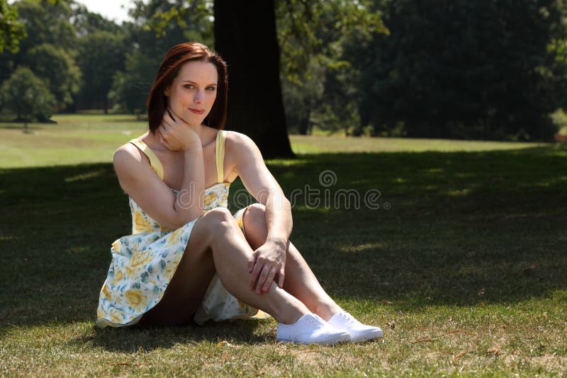 Beautiful young woman sitting on grass in park