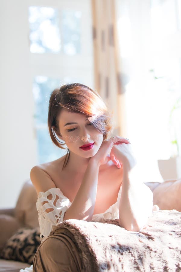 Beautiful young woman sitting on the sofa and smiling in the lux