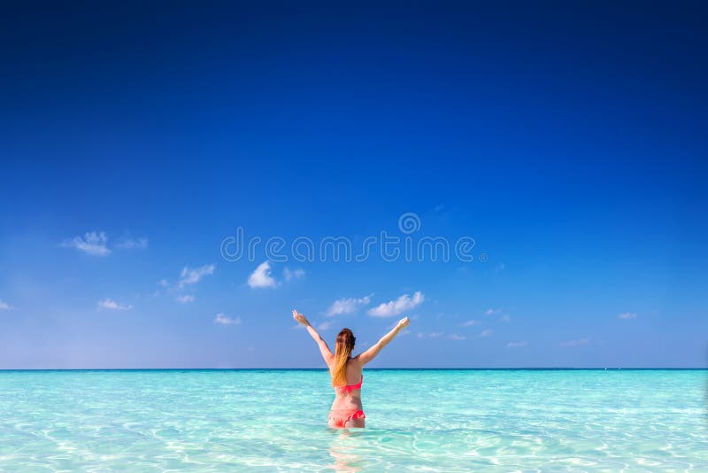 Beautiful young woman standing in the ocean with hands raised. Maldives royalty free stock images Beautiful young woman standing in the ocean with hands raised. Maldives royalty free stock images