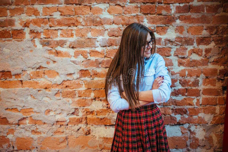 Beautiful young woman stands near the old brick wall. Youth styl