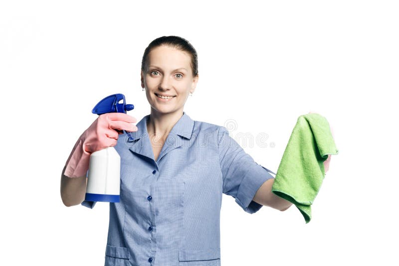 A beautiful young woman in the uniform of a maid holds a rag and spray for washing windows and looks at them in surprise. Isolated on a white background.