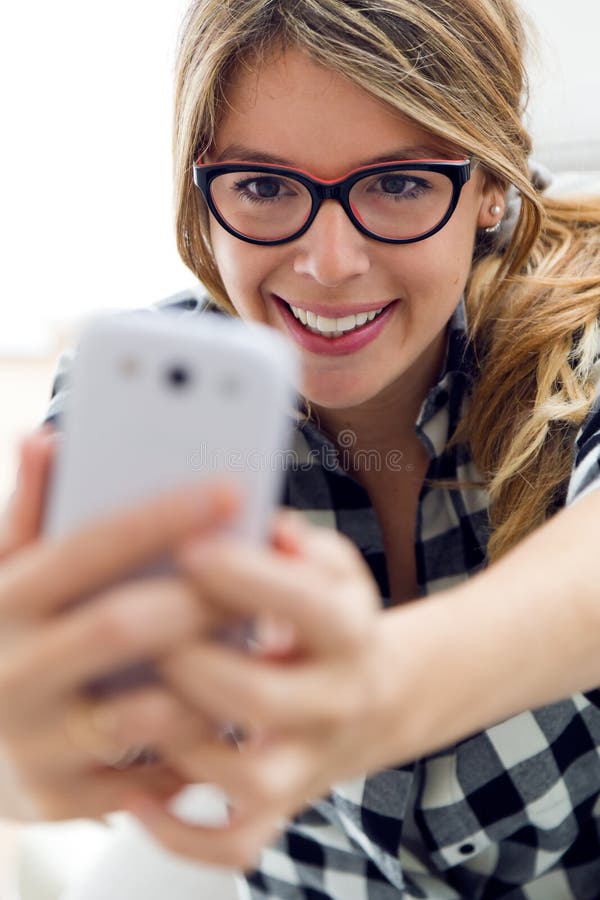 Beautiful young woman using her mobile phone at home. stock images