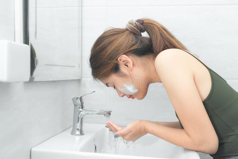 Beautiful Young Woman Washing Her Face Splashing Water In A Bathroom