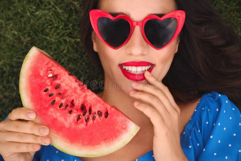 Beautiful young woman with watermelon on green grass outdoors, top view