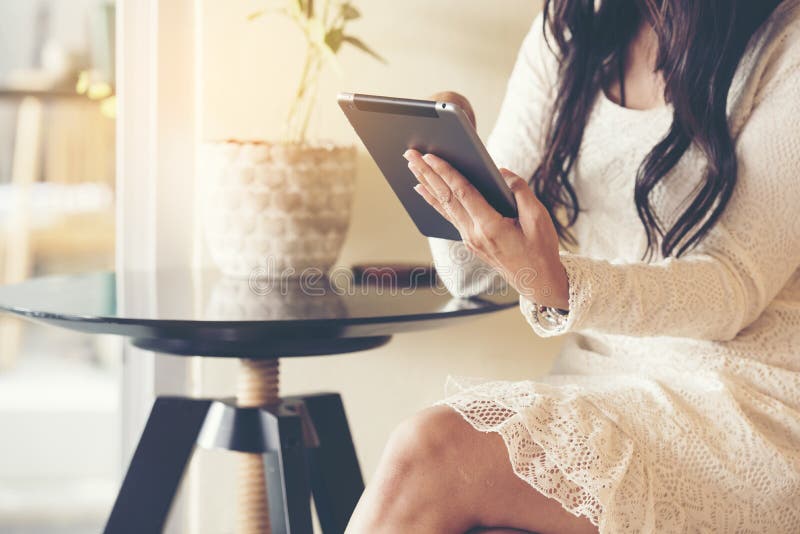 Beautiful young woman wear white lace dress using Ipad while sitting in coffee shop stock photo Beautiful young woman wear white lace dress using Ipad while sitting in coffee shop stock photo