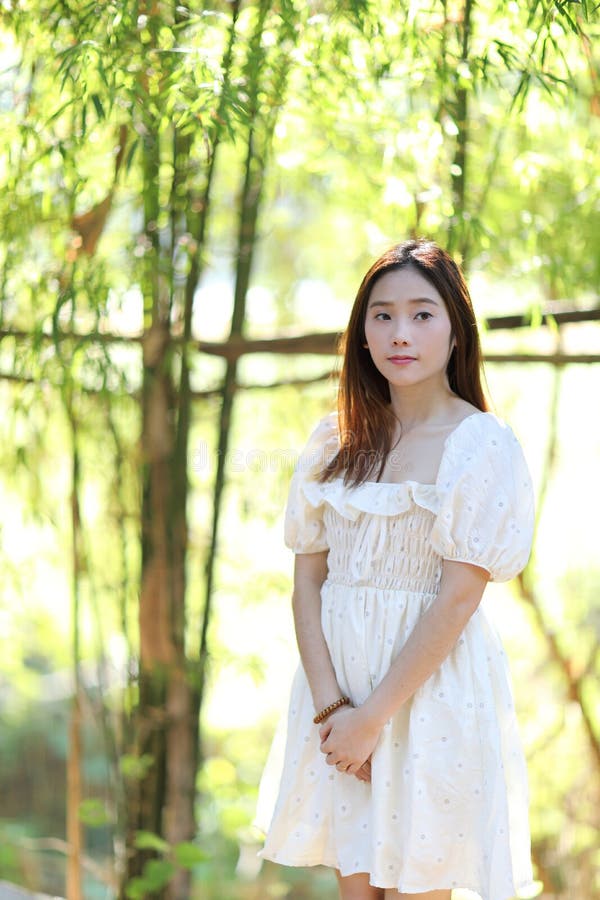 Beautiful young woman with white dress on bamboo forest background