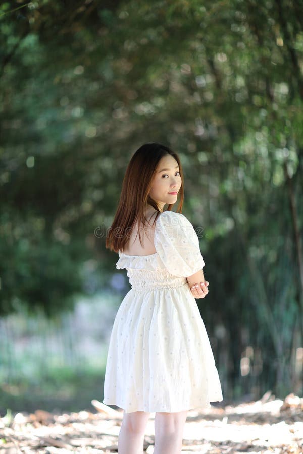 Beautiful young woman with white dress on bamboo forest background