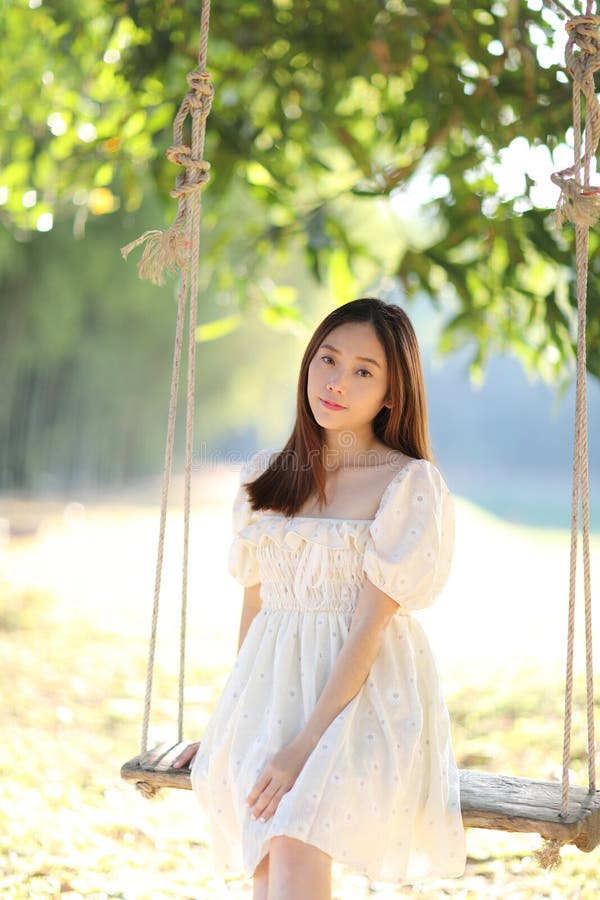 Beautiful young woman with white dress on swing