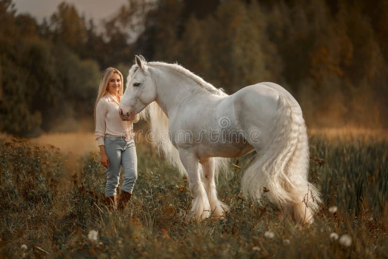 Beautiful young woman with white tinker cob in an autumn