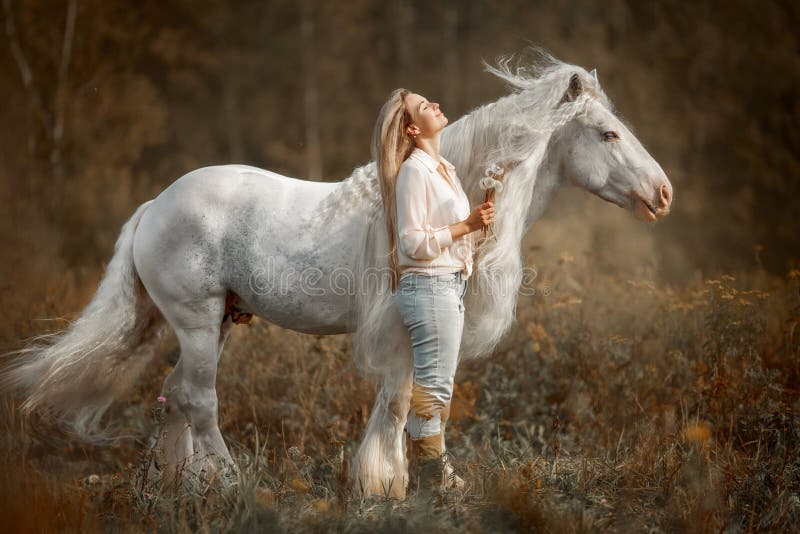 Beautiful young woman with white tinker cob in an autumn