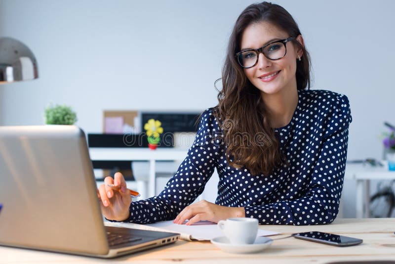 Beautiful young woman working with laptop in her office.