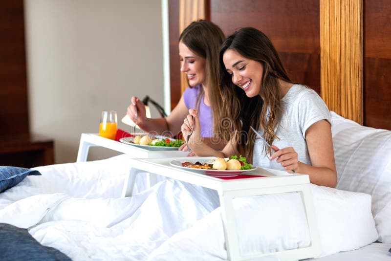 Beautiful young women eating in bed