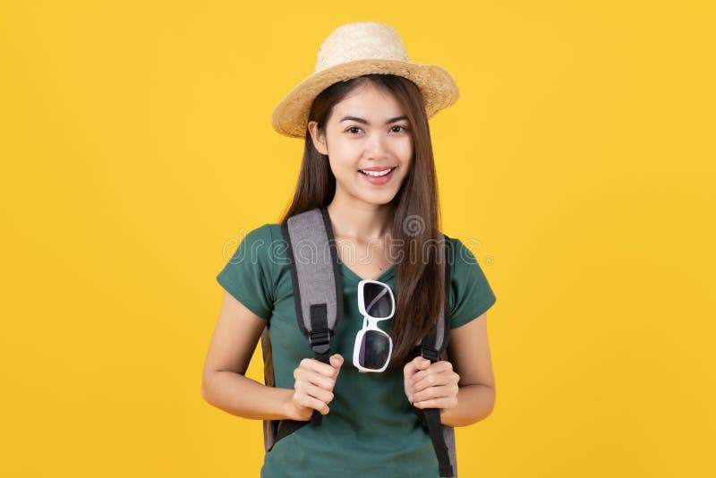 Beauty asian teenager in green tee shirt is backpack traveller isolated on yellow background in studio