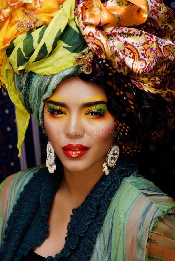 Beauty bright woman with creative make up, many shawls on head like cubian, ethno look closeup