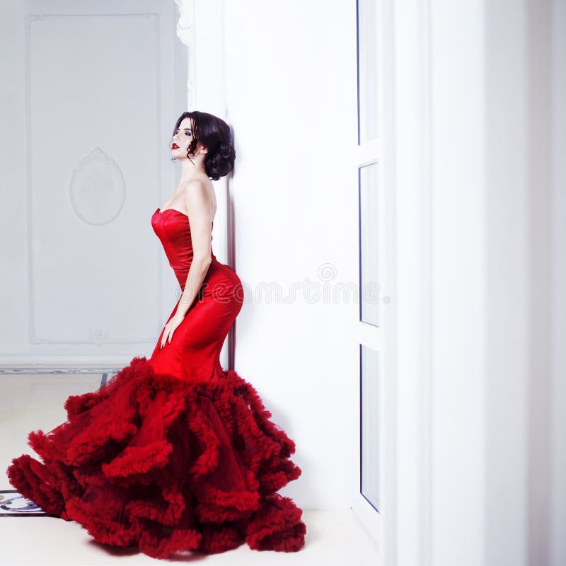 Beauty Brunette model woman in evening red dress. Beautiful fashion luxury makeup and hairstyle. Seductive silhouette