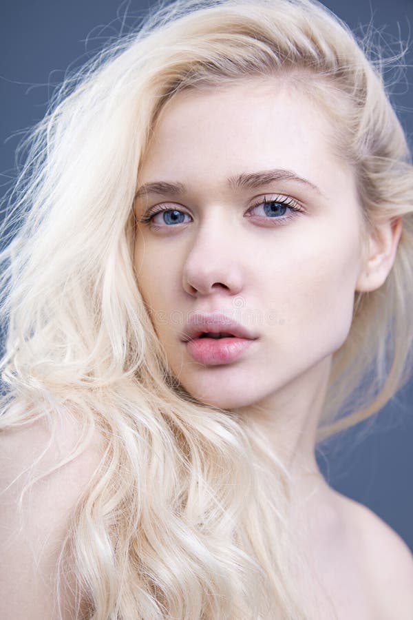 Beauty close up portrait of young beautiful blond woman face natural makeup, looking at camera, grey background.